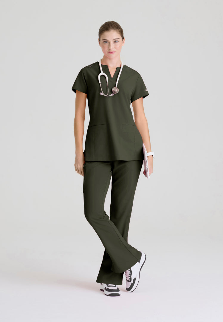 Woman wearing a Skechers olive green medical scrub set (SKT259 top and SKP623 pant) with a stethoscope on a white background