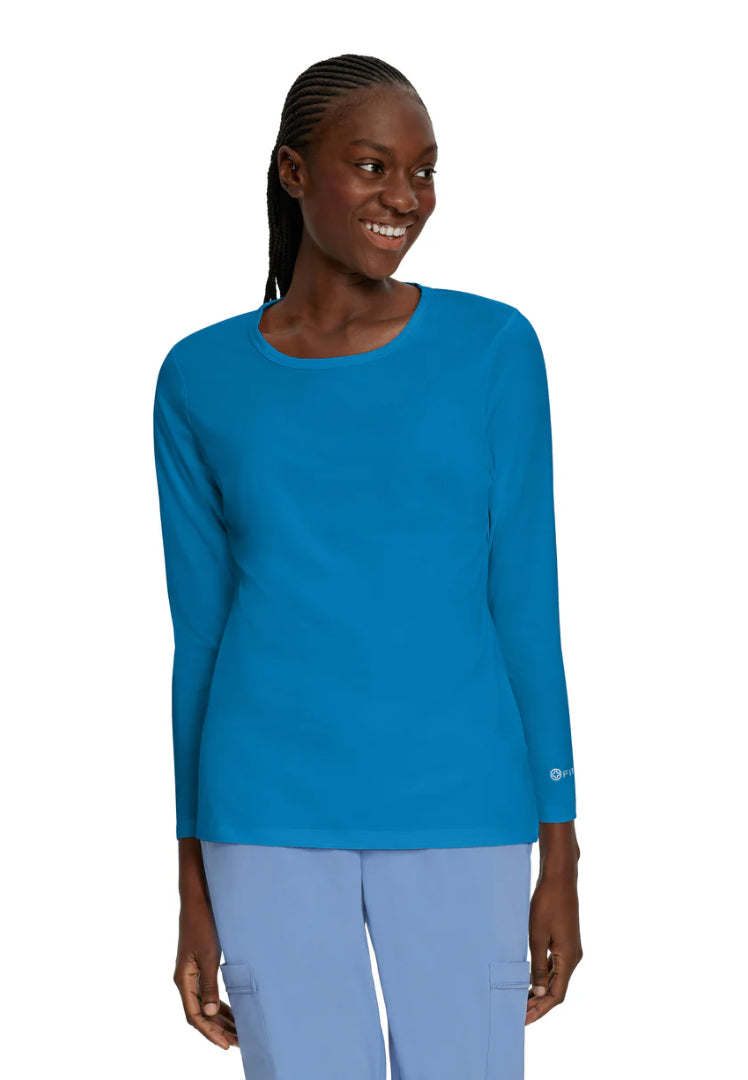 Woman wearing a White Cross 207 long-sleeve underscrub in regal blue with ciel blue pants on a white background