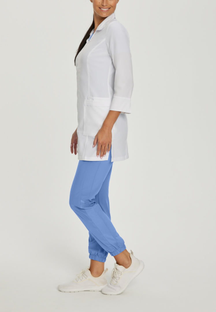 Person wearing a White Cross 2417 lab coat and blue pants on a light gray background