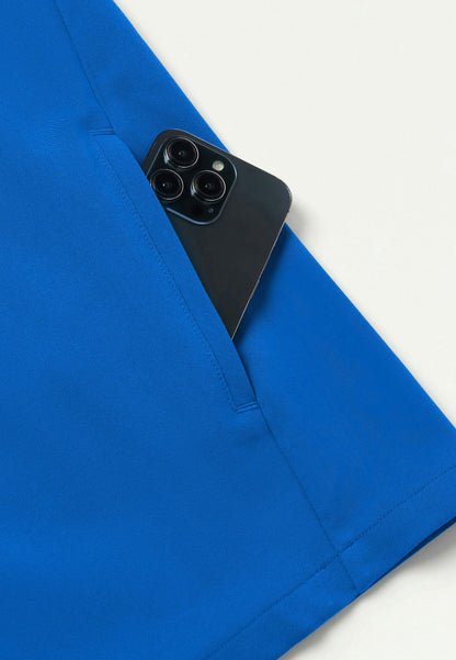 Detailed view of Jaanuu royal blue Platt scrub top with b lack smartphone peeking out of the garment pocket