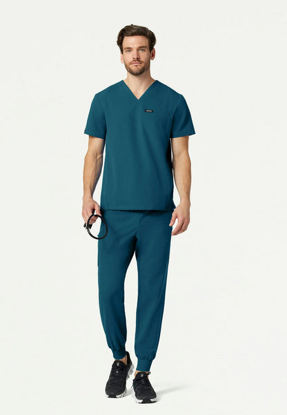 Man wearing a caribbean blue Jaanuu scrub set on a white background