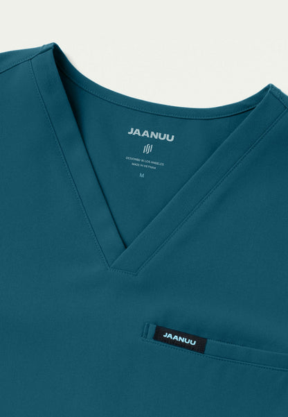 detail view of caribbean blue men's Platt scrub top with 'Jaanuu' branding on a white background