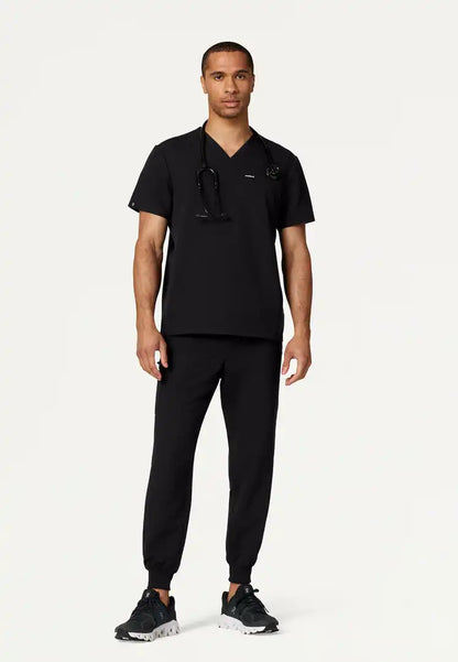 Full body image of a man wearing a black Jaanuu scrub set on a white background