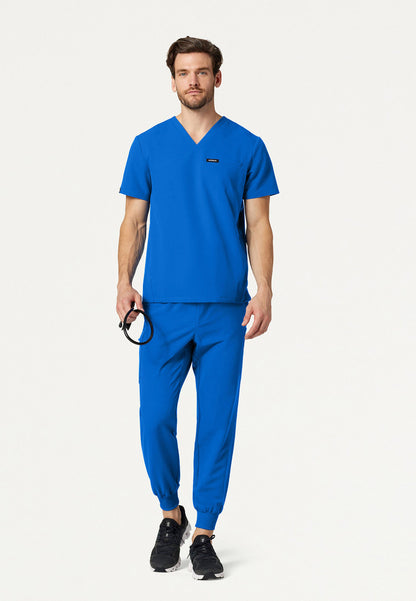 Man wearing a Jaanuu royal blue scrub set on a white background