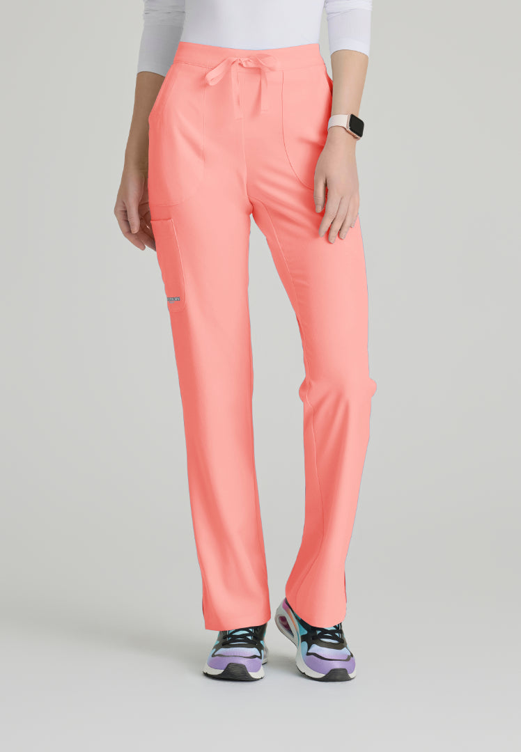 Woman wearing Skechers SK201 Coral Fizz scrub pants on a light gray background