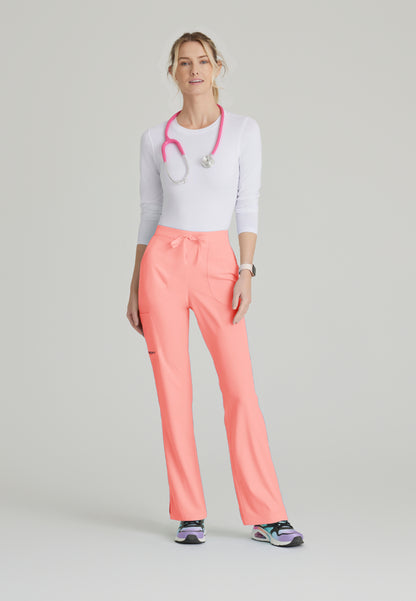 Woman wearing a white underscrub shirt and Skechers SK201 Coral Fizz scrub pants, standing against a light gray background.