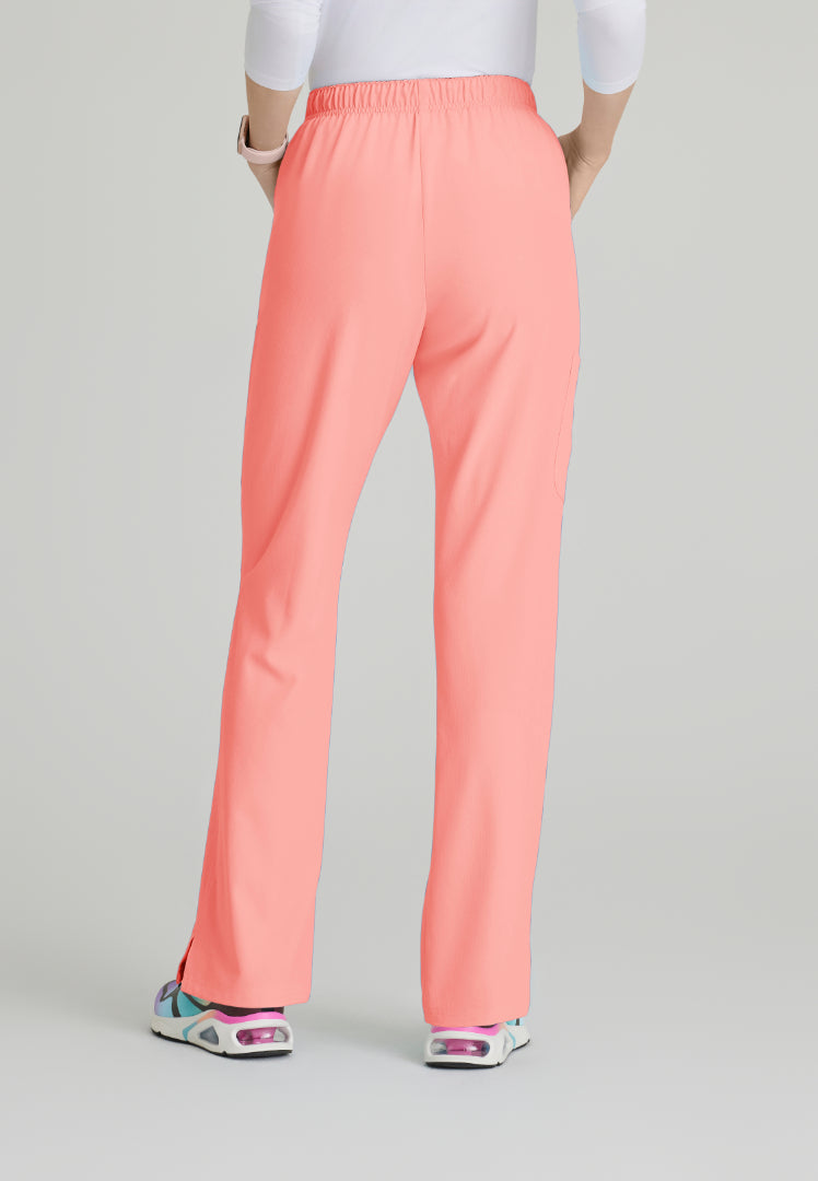 Back view of a woman wearing Skechers SK201 scrub pants in Coral Fizz on a plain background