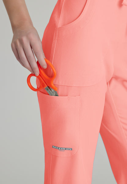 Detailed pocket view of a woman wearing Skechers SK201 scrub pants in Coral Fizz on a plain background
