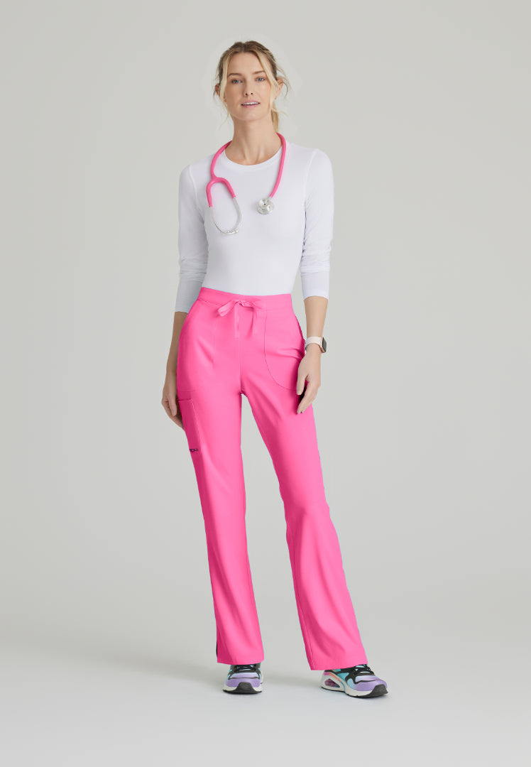 Woman wearing a white underscrub shirt with rolled-up sleeves, Skechers SK201 Passion Pink scrub pants, and a stethoscope on a light gray background
