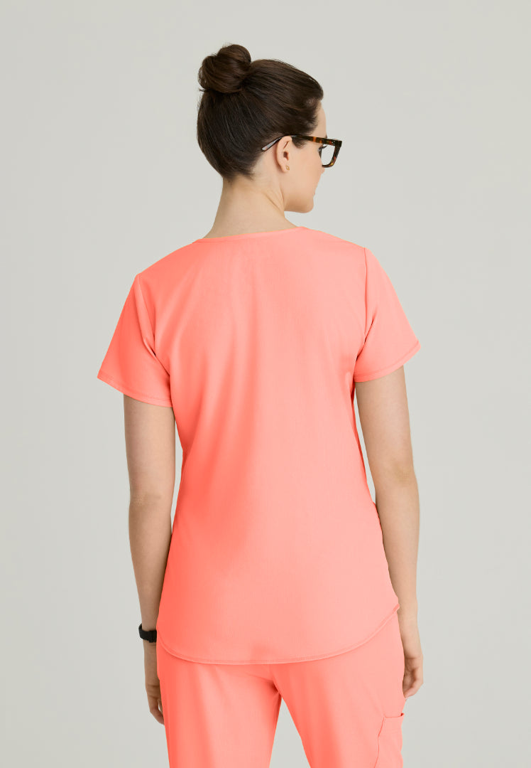 Back view of a woman wearing a Skechers Coral Fizz scrub set (SK101 scrub top and SK201 scrub pant) colored outfit on a plain background