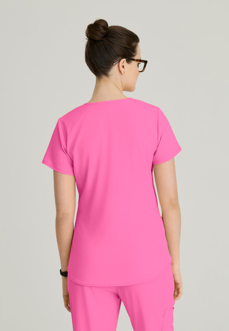 Back view of a woman wearing a Skechers SK101 Passion Pink scrub shirt on a plain background