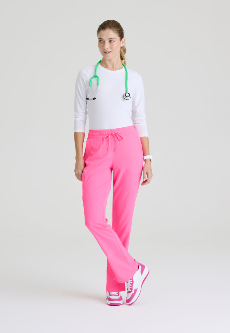 Woman wearing a white underscrub and Skechers Passion Pink SKP623 scrub pants with a green stethoscope around her neck on a light gray background