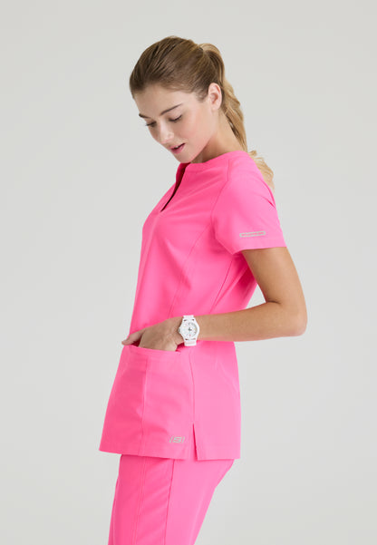 Side view of a woman wearing a Skechers SKT259 Passion Pink scrub shirt on a light gray background