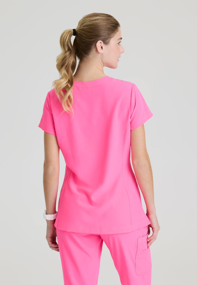 Back view of a woman wearing a Skechers SKT259 Passion Pink scrub shirt on a plain background
