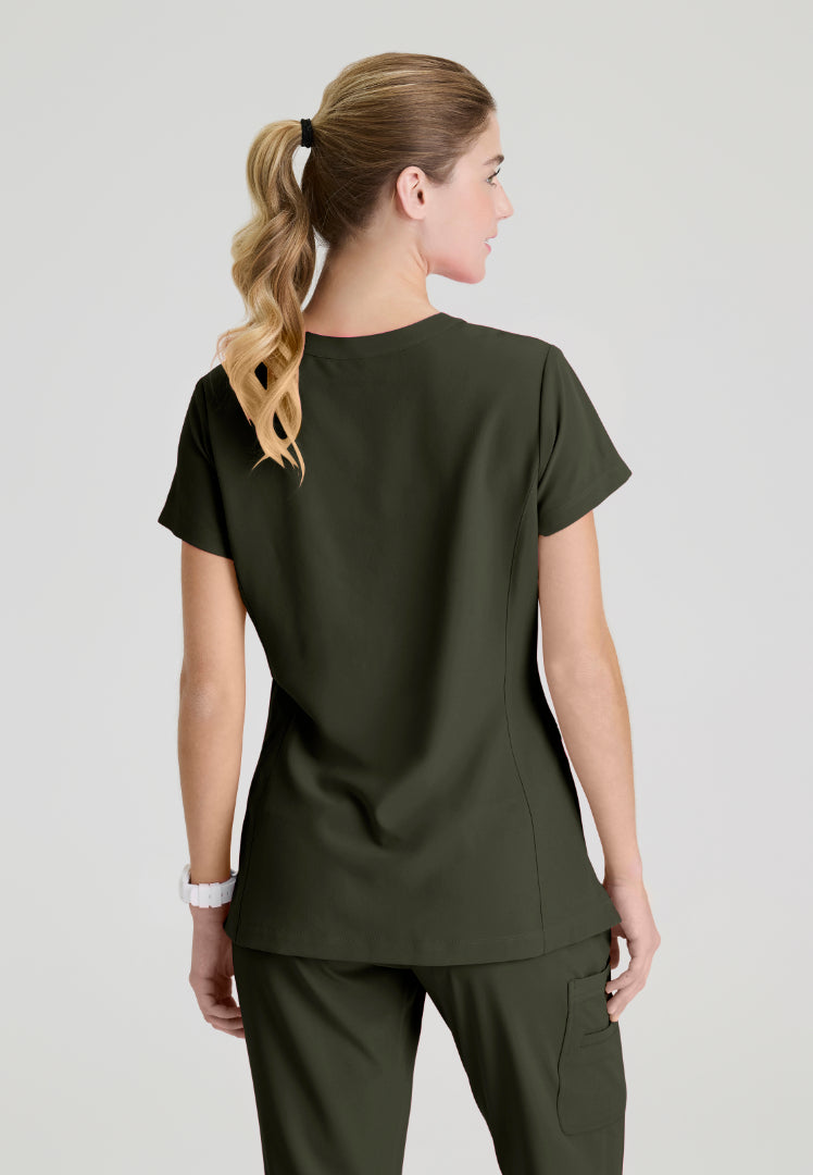 Back view of a woman wearing a Skechers SKT259 olive green scrub shirt on a plain background