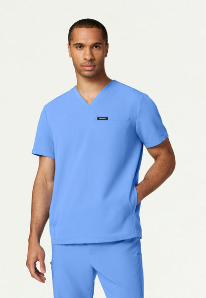 Man wearing a ciel blue Jaanuu Platt v-neck scrub shirt on a white background